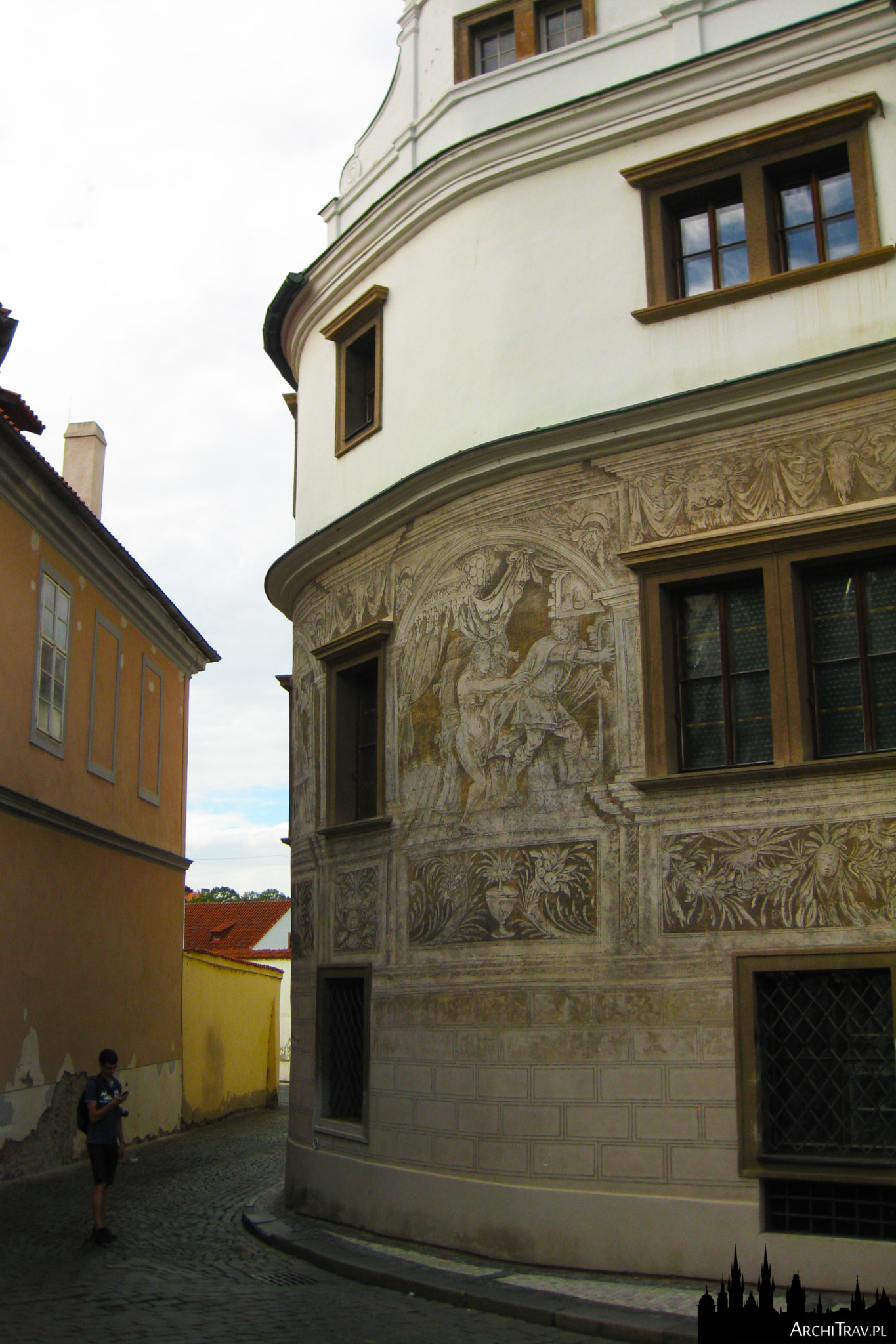 uliczka w Pradze, na pierwszym planie zaokrąglony budynek, a na nim freski