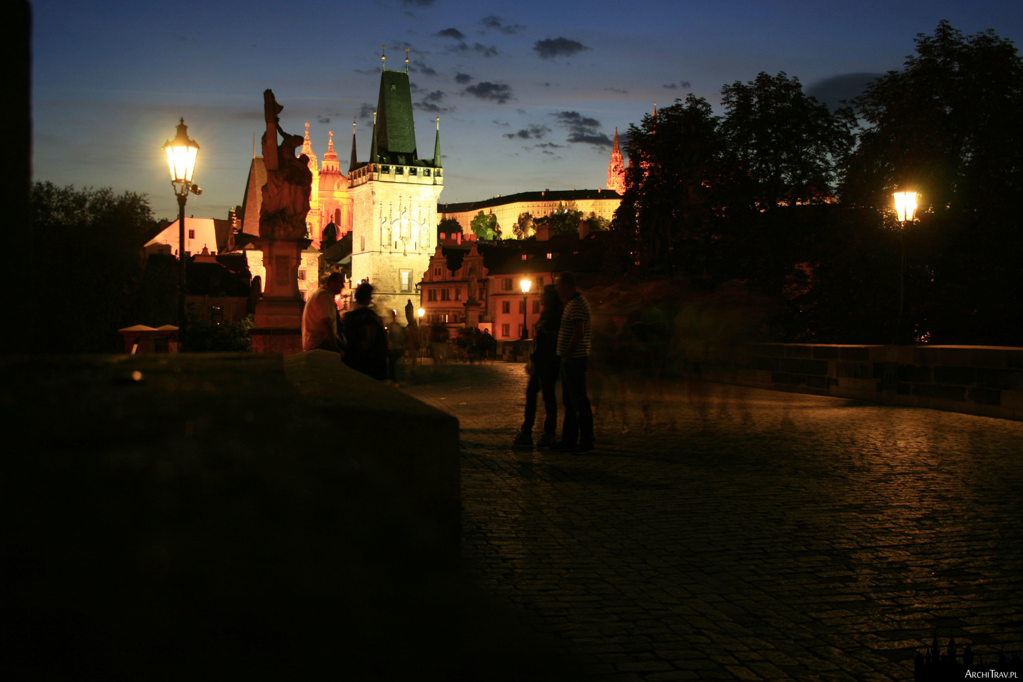 Most Karola w Pradze w nocy, mocno oświetlona Wieża Małostrańska